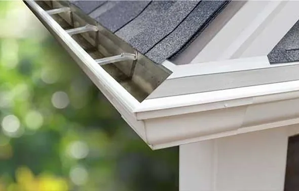 A close-up of a metal ladder tool inserted into a white gutter for cleaning.